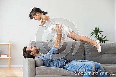 Smiling father lifting up carefree child daughter playing at hom Stock Photo