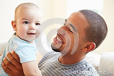 Smiling Father Playing With Baby Son At Home Stock Photo