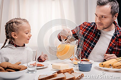 smiling father pouring juice to happy little daughter Stock Photo