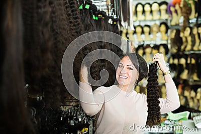 Smiling female assistant selling natural wigs Stock Photo