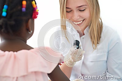 Smiling female doctor checking skin of little afro girl. Stock Photo