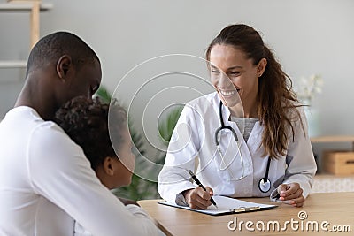 Smiling female doctor listen cute african boy make notes Stock Photo