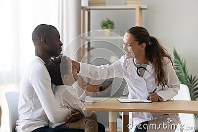 Smiling female pediatrician stroking head of cute small preschool patient. Stock Photo