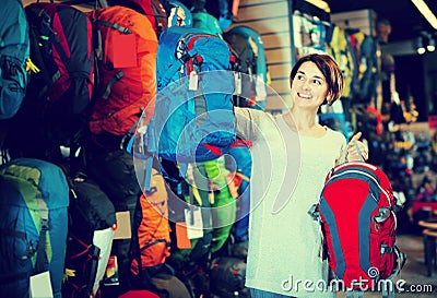Smiling female shopper examining rucksacks in sports equipment s Stock Photo