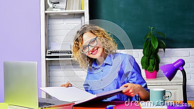 Smiling female teacher or student in classroom. Female teacher sitting at desk with book. World teachers day. Education Stock Photo