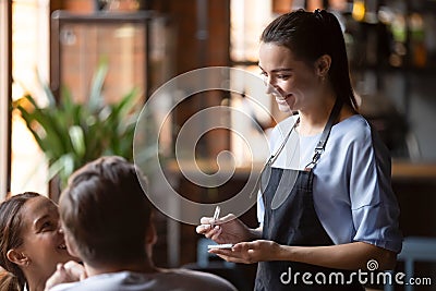 Smiling female waitress take order talk to clients couple Stock Photo