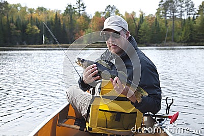 Smiling fisherman in a canoe on a northern Minnesota lake holds Stock Photo