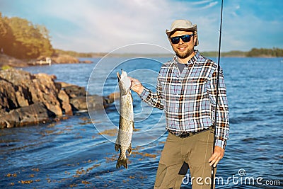 Smiling fisherman with caught pike fish in hand Stock Photo