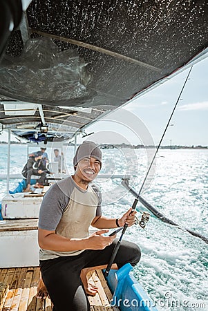 smiling fisherman holding a cell phone while fishing at sea Stock Photo