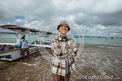 smiling fisherman standing with crossed hands on the shore Stock Photo