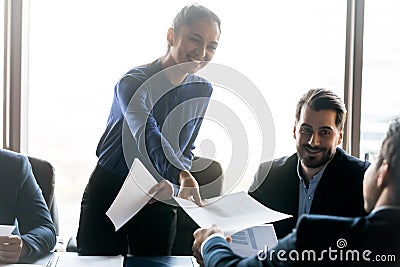 Smiling friendly businesswoman giving handout material to employee at meeting Stock Photo