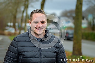 Smiling friendly young man standing in an urban street Stock Photo