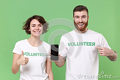 Smiling friends couple in volunteer t-shirt isolated on green background. Voluntary free work assistance help charity Stock Photo