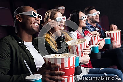 smiling friends in 3d glasses with popcorn and soda watching movie Stock Photo