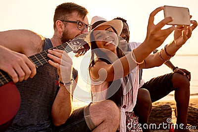 Smiling friends photographing with crazy musician on beach Stock Photo