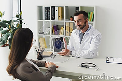 smiling general practitioner showing patient ipad Editorial Stock Photo