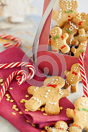 Smiling gingerbread men in a gift box with a candy cane close-up. Christmas cookies on Christmas blue light background. Stock Photo