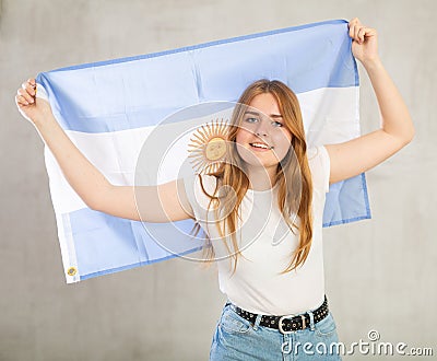 smiling girl in arms raised above head holds canvas of national flag of Argentina Stock Photo