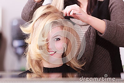 Smiling girl with blond wavy hair by hairdresser in beauty salon Stock Photo