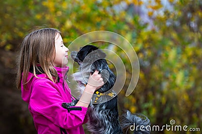 A smiling girl of Caucasian appearance holds a small papillon dog in her arms. Walk in the park Stock Photo