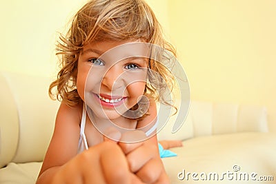 Smiling girl in cosy room, stretches hands forward Stock Photo