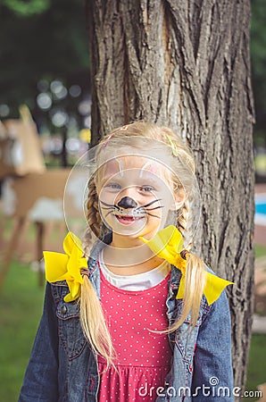 Smiling girl with face painting of mouse and long blond hair tail Stock Photo