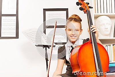 Smiling girl holds string to play violoncello Stock Photo