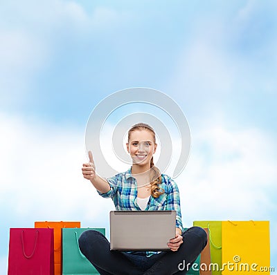 Smiling girl with laptop comuter and shopping bags Stock Photo