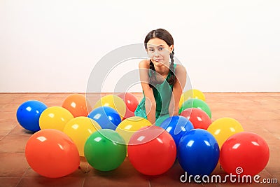 Smiling girl playing kneeling among inflating balloons Stock Photo