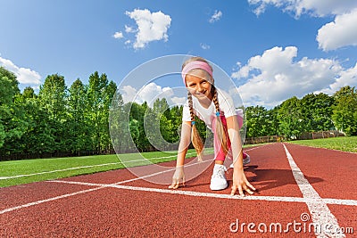 Smiling girl in position on knee ready to run Stock Photo