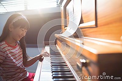 Smiling girl practicing piano in class Stock Photo