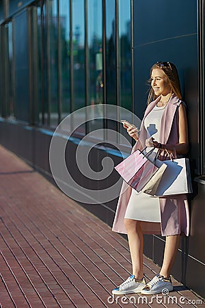 Smiling girl with shopping bags with phone in hand. Shopper. Sales. Concept of woman shopping Stock Photo