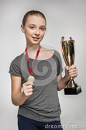 Smiling girl in sportswear holding trophy and medal Stock Photo