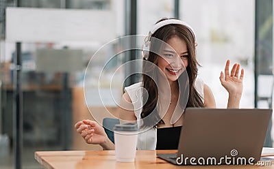 Smiling girl student wear wireless headphone study online with teacher, happy young asian woman learn language listen Stock Photo