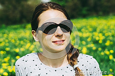 Girl sitting on the meadow with yellow dandelions Stock Photo