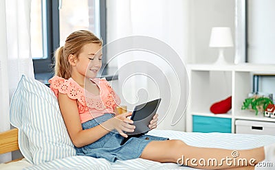 Smiling girl with tablet pc sitting on bed at home Stock Photo