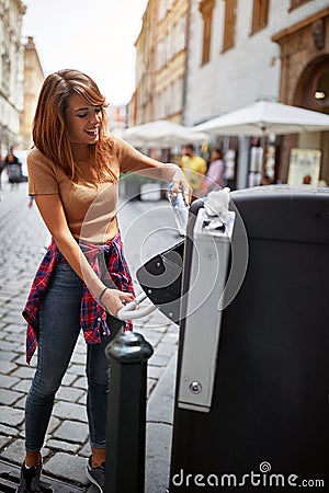 Smiling girl throwing garbage in recycling bin at city street Stock Photo