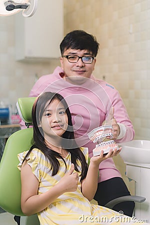 A smiling girl with thumb raised having teeth examination at dental clinic. People, medicine, stomatology and health care concept Stock Photo