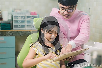 A smiling girl with thumb raised having teeth examination at dental clinic. People, medicine, stomatology and health care concept Stock Photo