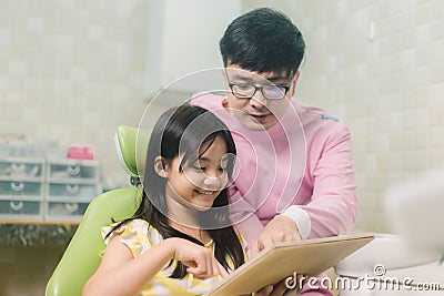 A smiling girl with thumb raised having teeth examination at dental clinic. People, medicine, stomatology and health care concept Stock Photo