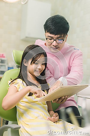 A smiling girl with thumb raised having teeth examination at dental clinic. People, medicine, stomatology and health care concept Stock Photo