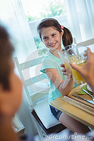 Smiling girl toasting glass of orange juice Stock Photo