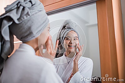 smiling girl wearing bathrobe and towel with fingers touching cheeks reflecting Stock Photo