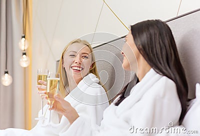 Smiling girlfriends with champagne glasses in bed Stock Photo