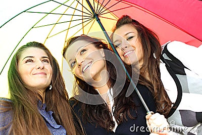 Smiling girlfriends under umbrella Stock Photo