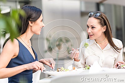 Smiling girls eating salad at desk Stock Photo