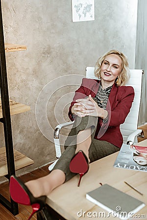 Smiling good-looking lady with blue eyes resting on white armchair Stock Photo