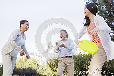 Smiling Granddaughter with grandparents playing Frisbee in the park Stock Photo