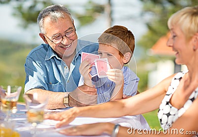 Smiling Grandfather playing cards with grandson Stock Photo