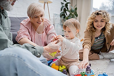 smiling grandparents giving toys to toddler Stock Photo